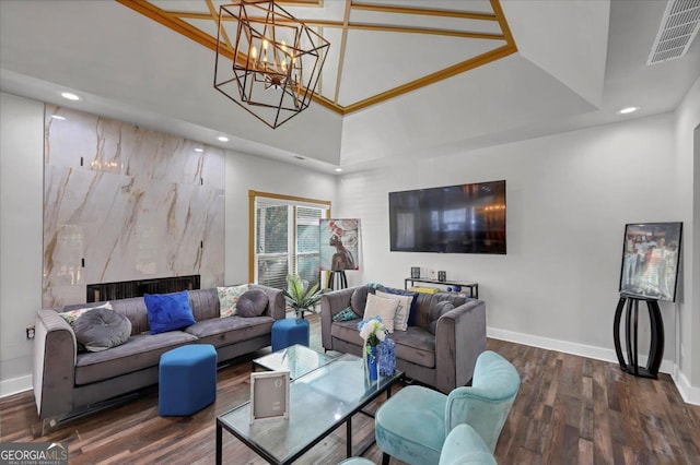 living room featuring a towering ceiling, a chandelier, dark hardwood / wood-style floors, and a high end fireplace