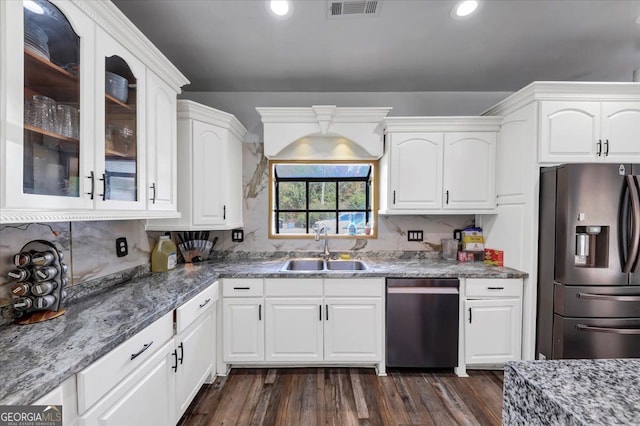 kitchen with appliances with stainless steel finishes, sink, white cabinetry, dark stone countertops, and dark wood-type flooring