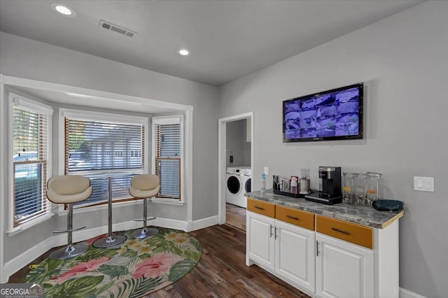 interior space featuring white cabinetry, dark hardwood / wood-style floors, light stone counters, and washer and dryer