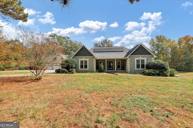 ranch-style house featuring a front yard and solar panels