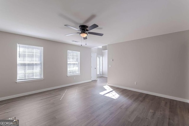 unfurnished room with ceiling fan, dark hardwood / wood-style floors, and a wealth of natural light