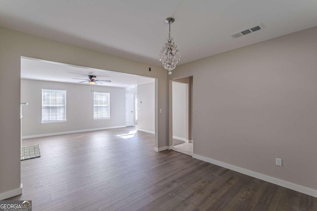 empty room featuring ceiling fan with notable chandelier and hardwood / wood-style flooring