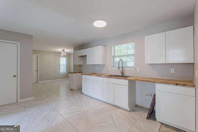 kitchen featuring white cabinets, sink, and wooden counters