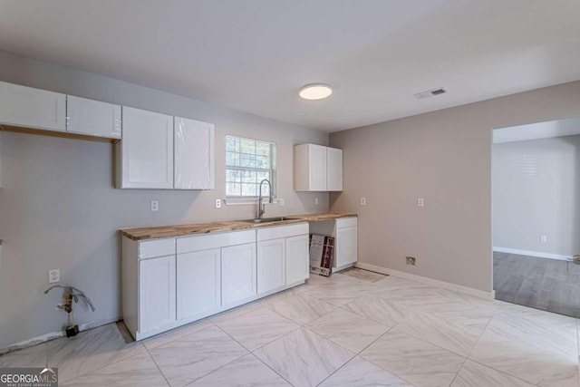 kitchen with white cabinets, sink, and wood counters