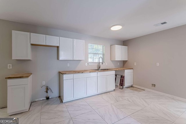 kitchen featuring white cabinets, sink, and wood counters