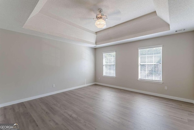 spare room featuring ceiling fan, a tray ceiling, wood-type flooring, and a textured ceiling