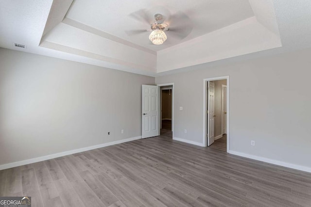 unfurnished bedroom featuring ceiling fan, hardwood / wood-style flooring, and a tray ceiling