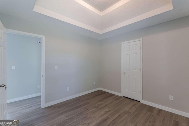 empty room featuring wood-type flooring and a raised ceiling