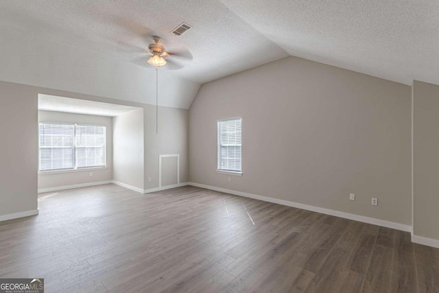 additional living space featuring a textured ceiling, ceiling fan, vaulted ceiling, and dark hardwood / wood-style flooring