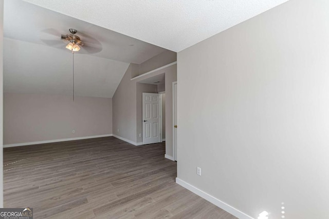 bonus room featuring lofted ceiling, a textured ceiling, light wood-type flooring, and ceiling fan