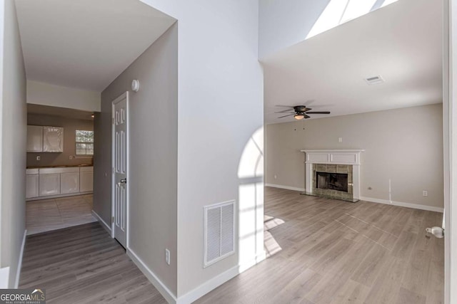 unfurnished living room featuring ceiling fan, light hardwood / wood-style flooring, and a fireplace