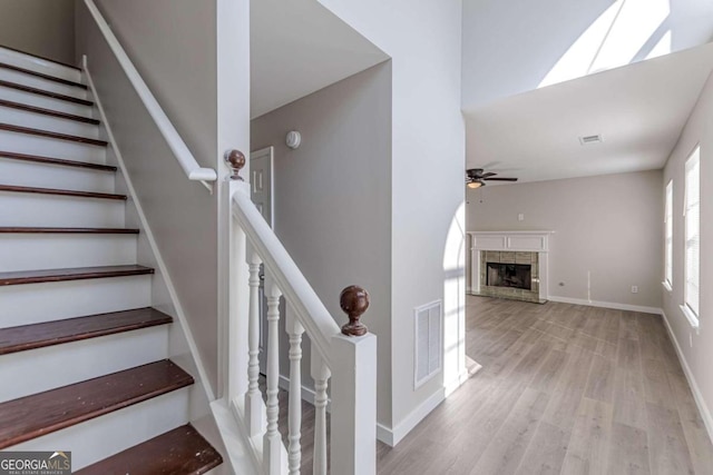 1983 Smithfield Ave, Ellenwood, GA 30294 - stairs with wood finished floors, visible vents, a fireplace with raised hearth, and a ceiling fan