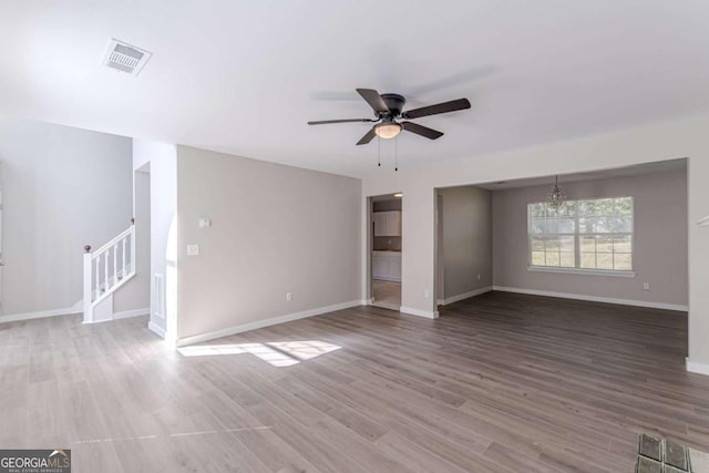 unfurnished living room featuring wood-type flooring and ceiling fan with notable chandelier