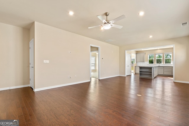 unfurnished living room with ceiling fan and dark wood-type flooring