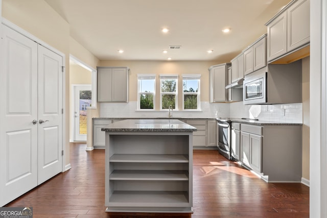 kitchen with a center island, gray cabinets, dark wood-type flooring, and stone counters