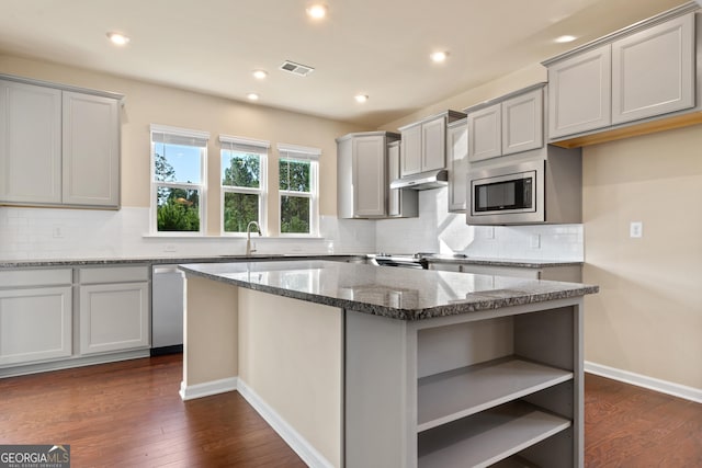 kitchen with tasteful backsplash, dark hardwood / wood-style flooring, a center island, and appliances with stainless steel finishes