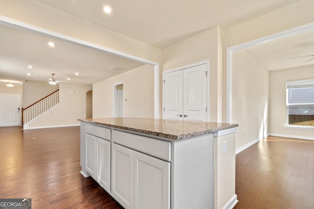 kitchen featuring light stone countertops, a kitchen island, dark hardwood / wood-style flooring, and white cabinetry