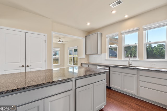 kitchen featuring dark hardwood / wood-style floors, a healthy amount of sunlight, sink, and dark stone counters