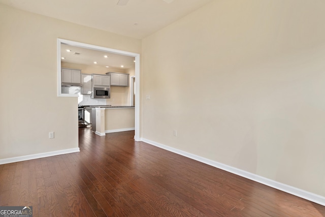 unfurnished living room with dark hardwood / wood-style floors and ceiling fan