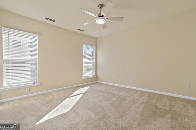 spare room with ceiling fan and light colored carpet