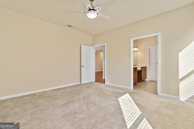 unfurnished bedroom with connected bathroom, light colored carpet, and ceiling fan