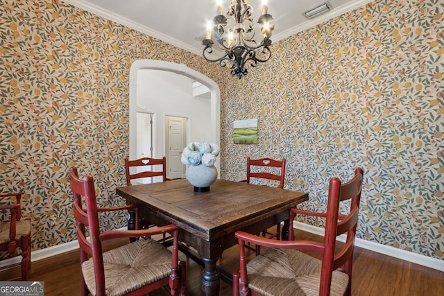 dining area featuring a notable chandelier, ornamental molding, and dark wood-type flooring