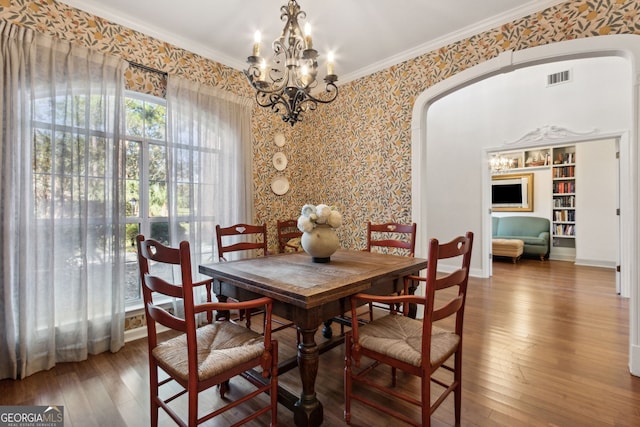 dining room featuring crown molding, built in shelves, a chandelier, and hardwood / wood-style floors