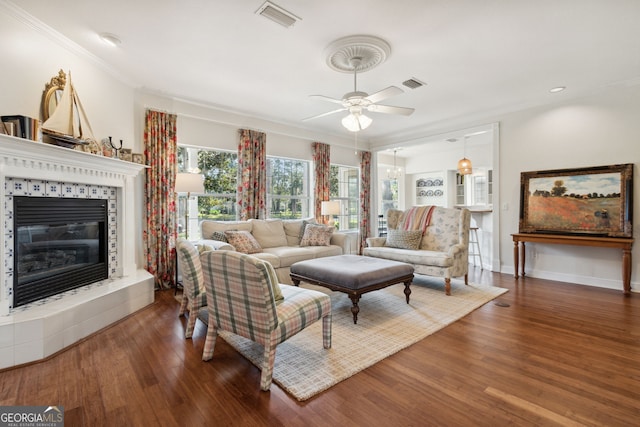 living room featuring ornamental molding, ceiling fan, a fireplace, and dark hardwood / wood-style flooring