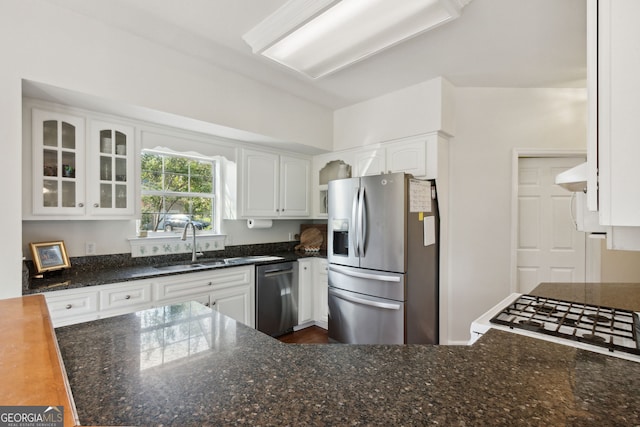 kitchen featuring appliances with stainless steel finishes, extractor fan, white cabinetry, vaulted ceiling, and sink