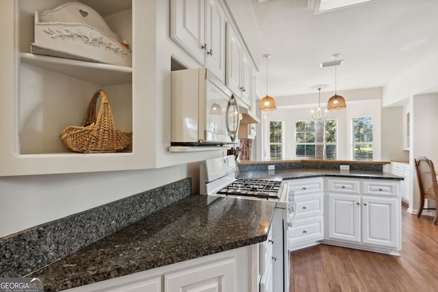 kitchen featuring wood-type flooring, white gas range oven, decorative light fixtures, white cabinets, and an inviting chandelier