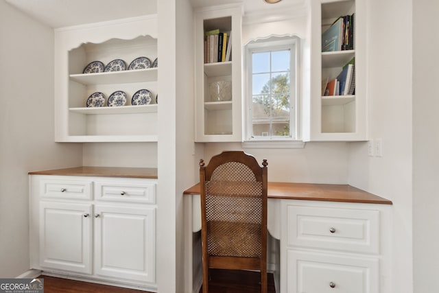 office with built in desk and dark hardwood / wood-style floors