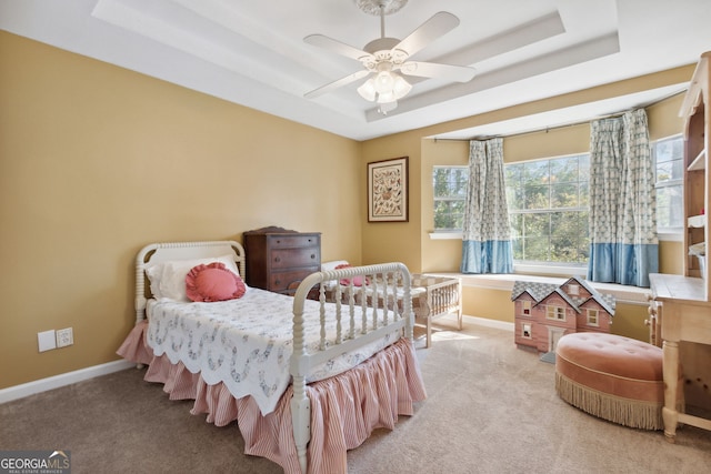 bedroom featuring a raised ceiling, light carpet, and ceiling fan