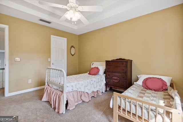 bedroom with light carpet, a tray ceiling, and ceiling fan