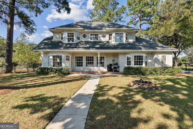 view of front facade with an outdoor fire pit and a front lawn