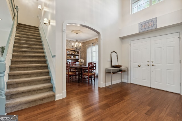 entrance foyer featuring a wealth of natural light, crown molding, dark hardwood / wood-style floors, and a high ceiling