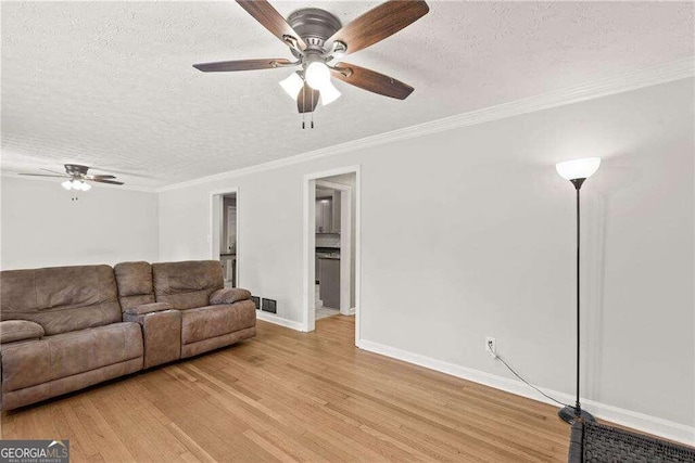 living room with a textured ceiling, ceiling fan, ornamental molding, and light hardwood / wood-style flooring