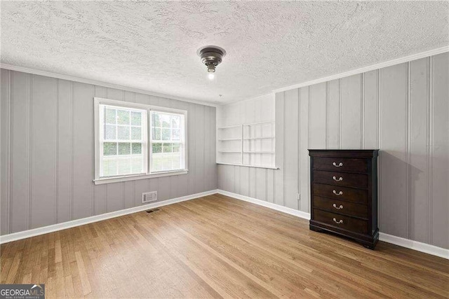 empty room with built in features, hardwood / wood-style floors, and a textured ceiling