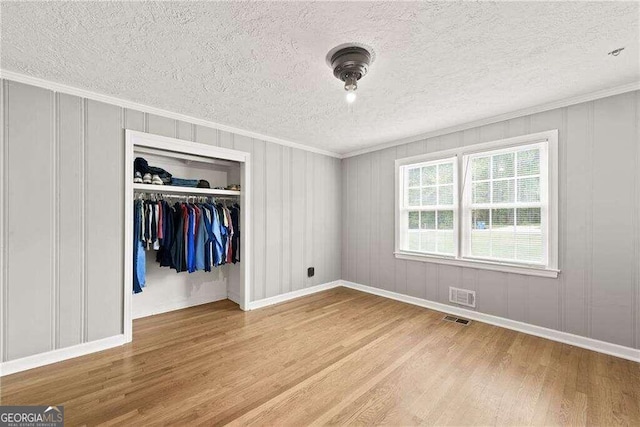 unfurnished bedroom featuring a closet, hardwood / wood-style flooring, ornamental molding, and a textured ceiling