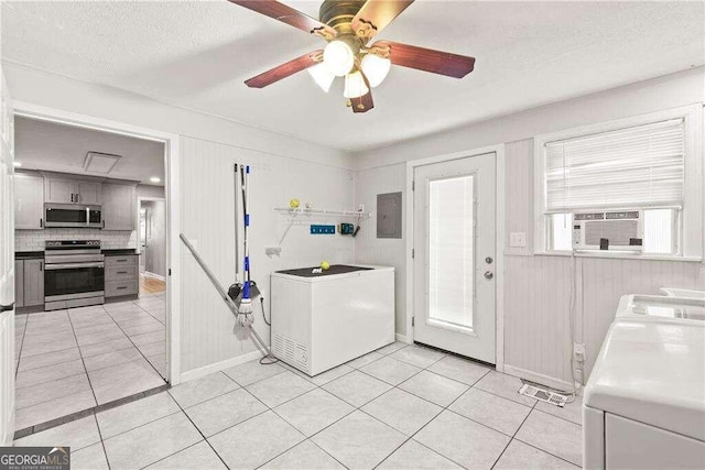 kitchen featuring ceiling fan, washer and clothes dryer, stainless steel appliances, light tile patterned floors, and a textured ceiling