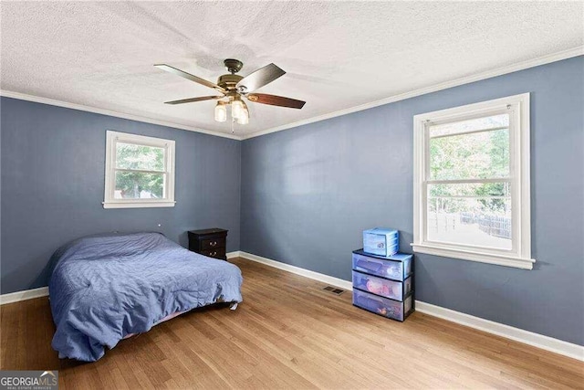 bedroom with ceiling fan, a textured ceiling, light hardwood / wood-style flooring, and multiple windows