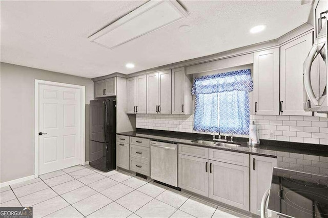 kitchen with light tile patterned flooring, decorative backsplash, gray cabinetry, sink, and dishwasher