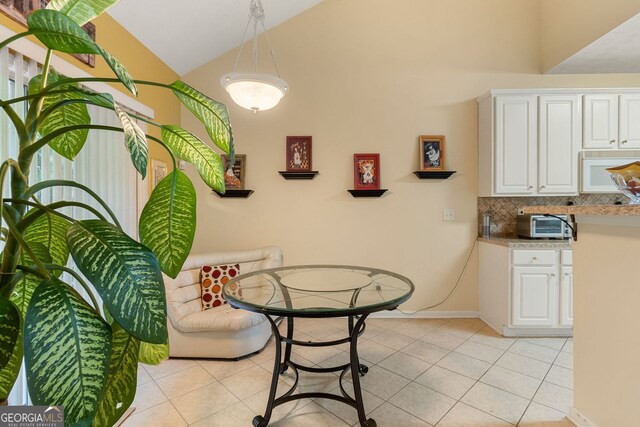 dining room with light tile patterned flooring and high vaulted ceiling