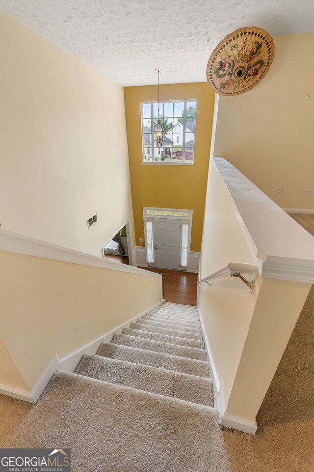 stairs with carpet and a textured ceiling