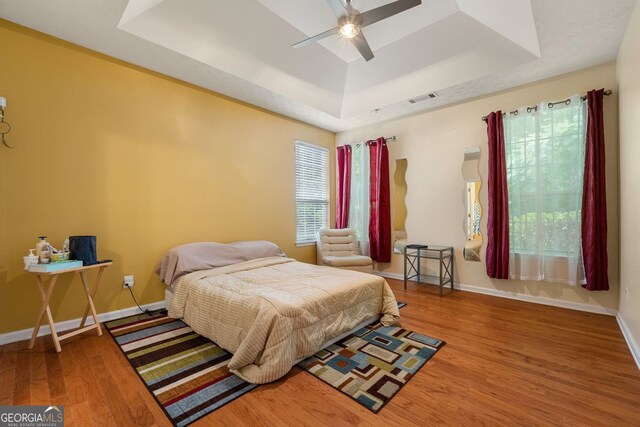 bedroom featuring ceiling fan, hardwood / wood-style flooring, and a raised ceiling