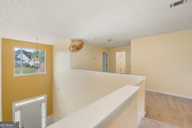 corridor featuring light colored carpet and a textured ceiling