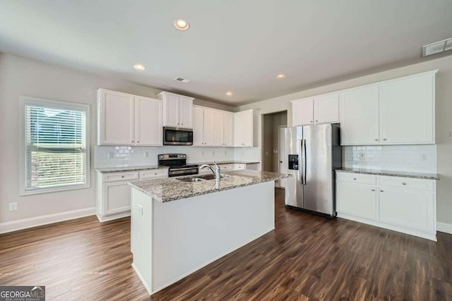 kitchen featuring a center island with sink, dark wood-type flooring, white cabinetry, appliances with stainless steel finishes, and light stone countertops