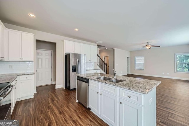 kitchen featuring dark wood-type flooring, a center island with sink, sink, stainless steel appliances, and white cabinetry