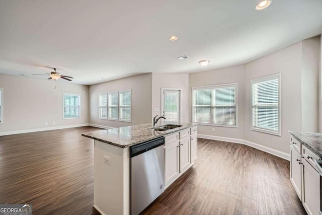 kitchen with an island with sink, stainless steel dishwasher, sink, dark hardwood / wood-style flooring, and white cabinetry