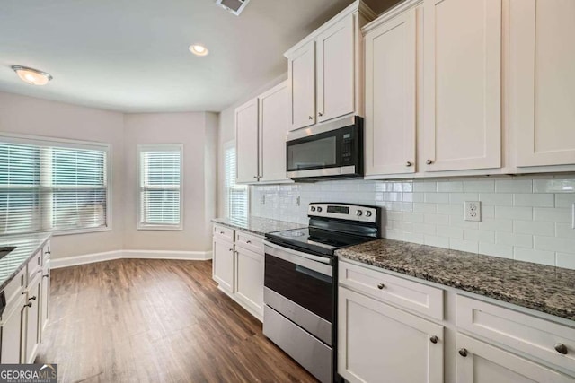 kitchen featuring tasteful backsplash, dark hardwood / wood-style flooring, dark stone countertops, stainless steel appliances, and white cabinets