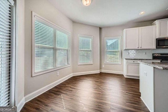 kitchen featuring dark hardwood / wood-style floors, appliances with stainless steel finishes, backsplash, and white cabinetry